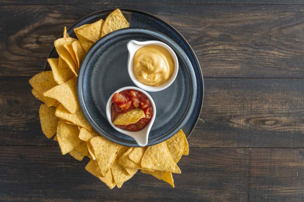 Teller mit Nachos und Schüsseln mit Dips