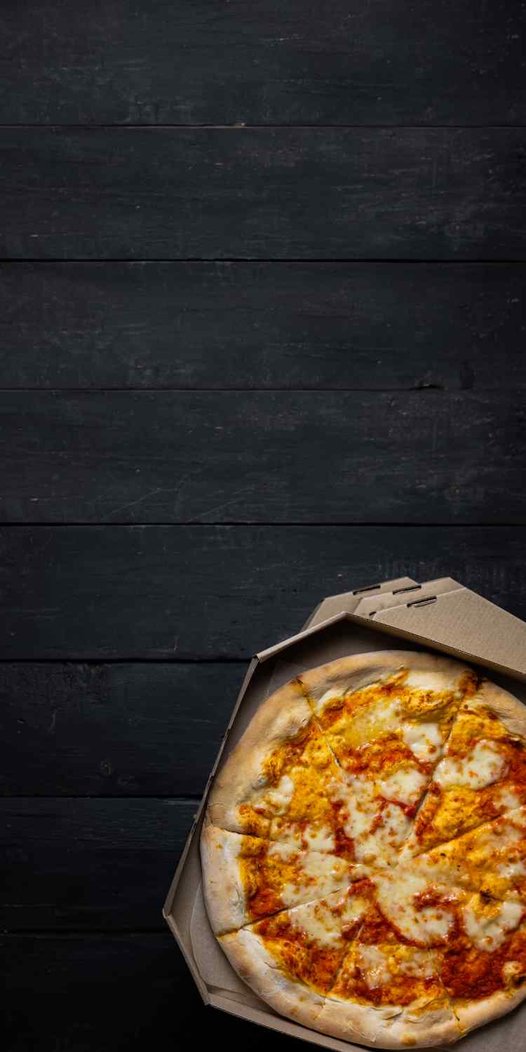 Pizza Margharita in einem Karton auf schwarzen Holzplanken