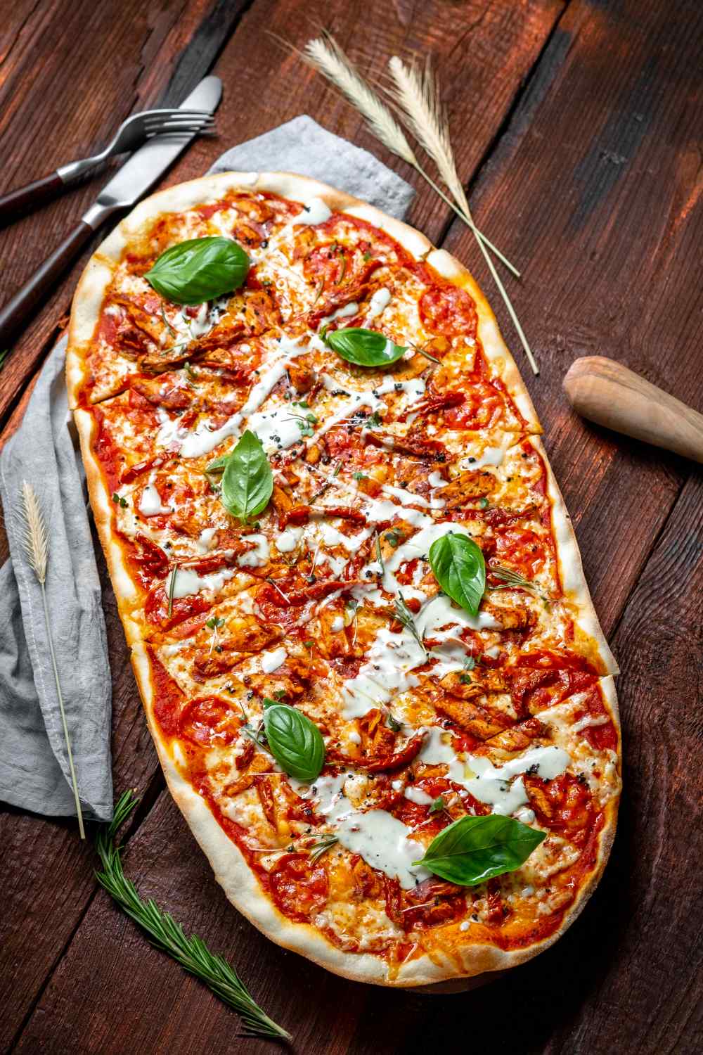Ovale Pizza mit Basilikum garniert