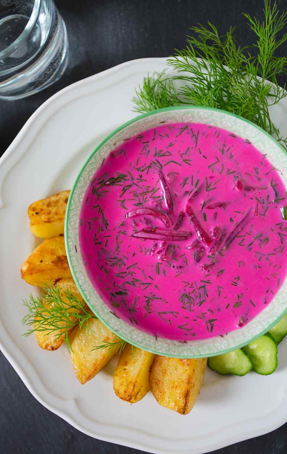 Pinke Suppe mit rote Beete Stücken mit Backofenkartoffeln und Gurken